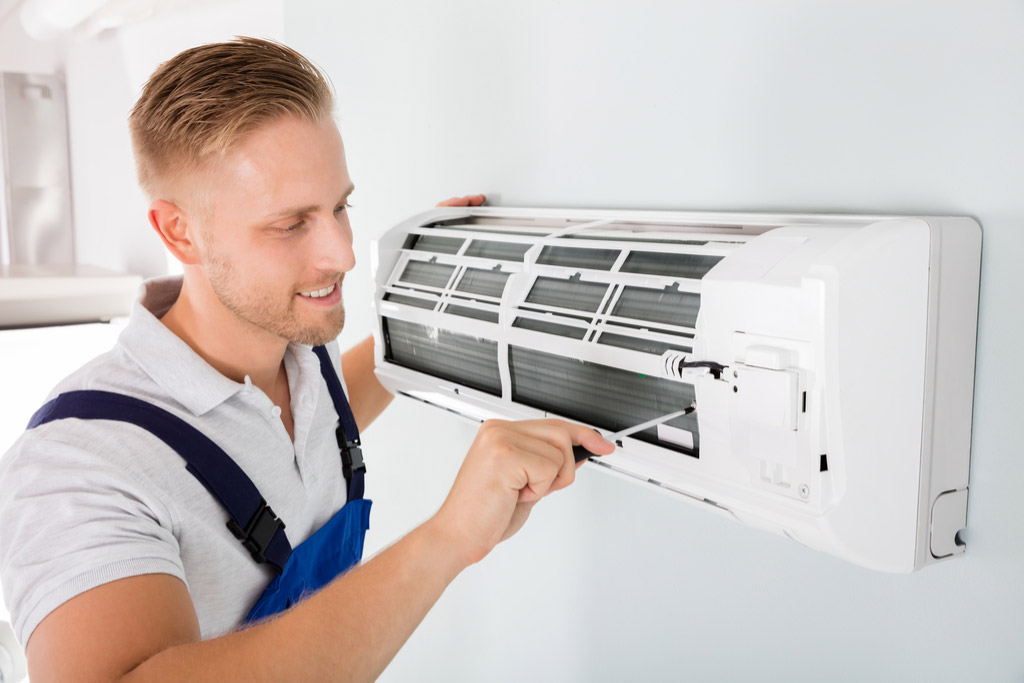 HVAC technician performing ductless air conditioning maintenance in Apache Junction