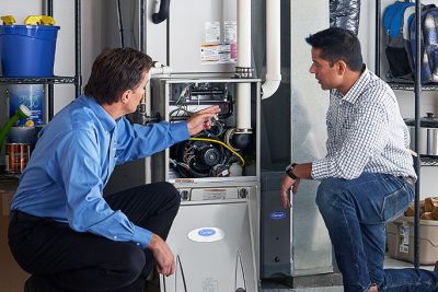 HVAC technician explaining furnace repair and maintenance to a homeowner in Apache Junction, AZ